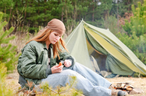 девушка сидит у походной палатки в лесу